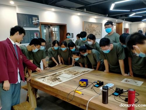 9.讲解员向学生介绍烙画作品