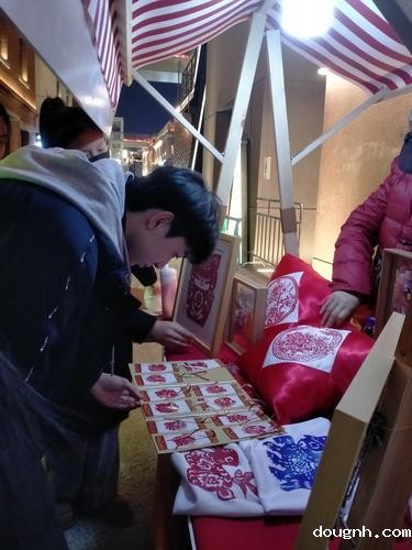 剪纸摊位前专注挑选的少年